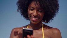 Close up relaxed black woman hold use smart phone watching social media at the beach 