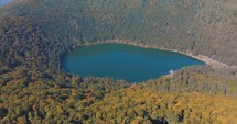 St. Ana's Lake, Transylvania, Romania - Stunning autumn scenery with colorful forest and idyllic volcanic lake - aerial orbit
