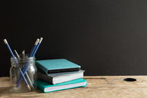 teal and gray books with pens on desk