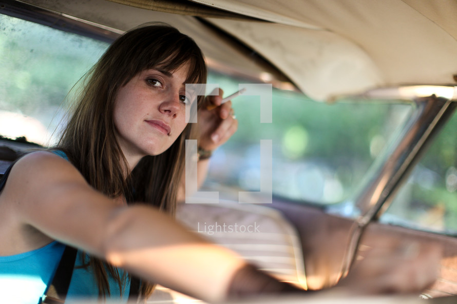 woman smoking a cigarette in a car