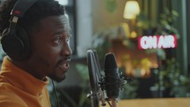 Joyous Black Man in Headphones Recording Podcast Interview in Studio
