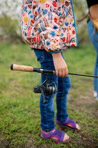 Little girl carrying a fishing pole 