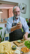 Senior chef removing artichoke leaves and talking on camera, giving online cooking lesson or filming food vlog in the kitchen. Vertical format clip
