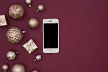 cellphone and gold ornaments on berry red