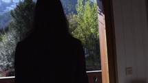 Woman at a ski chalet admires mountains window in Chamonix France, slow motion
