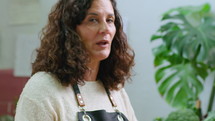 Female food blogger in apron smelling piece of blue cheese and cutting it for sandwich, talking on camera while filming video recipe or cooking class in the kitchen. Tilt-down shot
