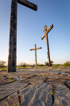 Three wooden crosses on stone and grass vertical