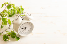 White alarm clock with white flowers on a white background