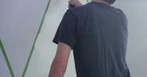 Man painting lines on bedroom wall - from behind - slow motion