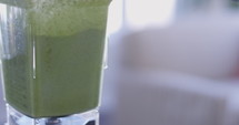 Finger pressing start on green smoothie blender - slow motion