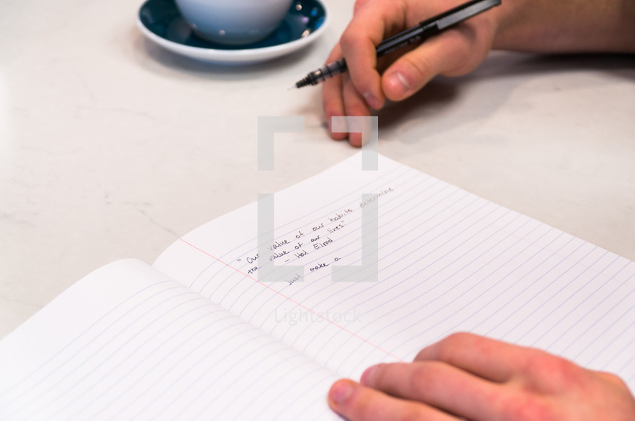 a man writing in a notebook while sitting in a coffee house 