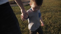 A father holding hands with his son while walking in slow motion.