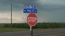 Stop sign, traffic sign on highway in midwest, rural America in Kansas farmland with distant storm clouds and cattle, cows in pasture.