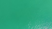 Top-down drone aerial view of bright blue sea water with sunlight reflections
