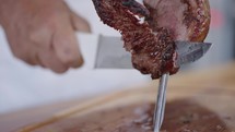 Close up of Picanha on a stick being cut in slow motion. Traditional Churrasco Brazilian Barbecue. 
