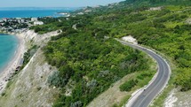 Vehicle Driving On Coastal Road In The Hill At The Coast Of Heros Beach In Balchik, Bulgaria With Scenic View Of Black Sea In Background. aerial