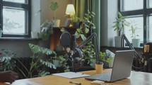 African American Podcaster Putting on Headphones and Talking in Mic in Studio
