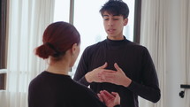 Young professional ballet dancers discussing choreography, creativity, practicing movements and smiling during rehearsal in studio
