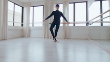 Young Latin male dancer doing passe, developpe and arabesque while performing ballet movements during rehearsal in studio. Zoom shot
