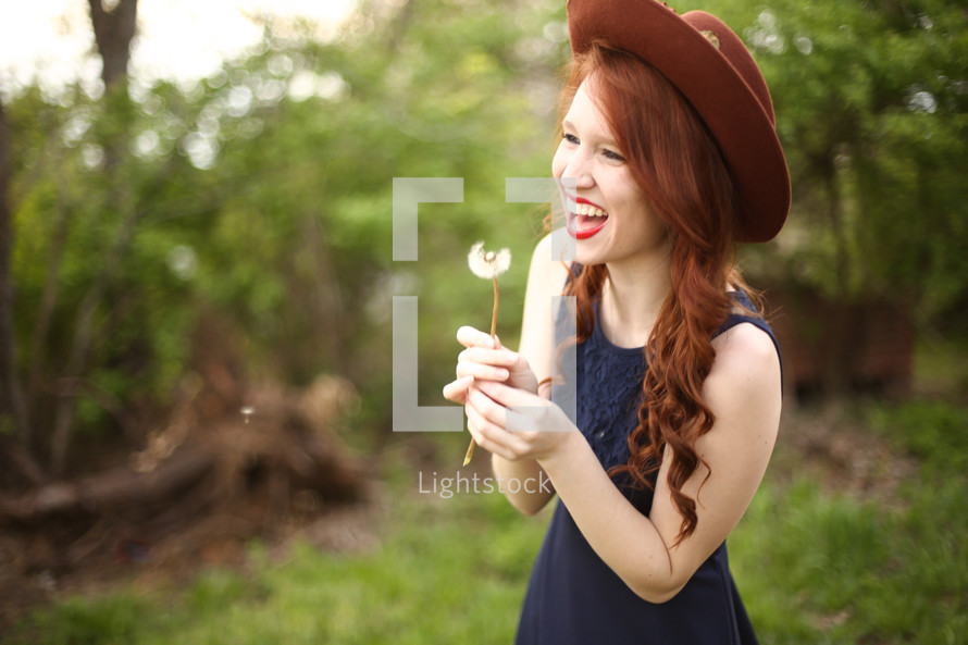 a woman blowing a dandelion outdoors 