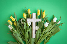 Cross on a bed of yellow and white tulips on a green background
