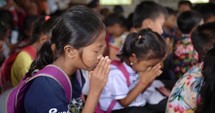 Close up of Southeast Asian elementary students praying.