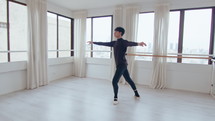 Young talended male dancer doing mesmerizing pirouettes, having ballet rehearsal at the studio. Zoom shot, full length
