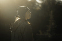 Woman walking through a forest at sunrise, hiking outdoors, walk in nature, active person