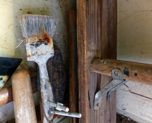 paint brush and old ladder that have served well, stored  in a garage corner 
