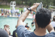 a man taking a picture with his cellphone at a swimming meet 