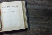 A Bible on a wooden table open to the New Testament.