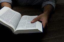 man reading the pages of a Bible 