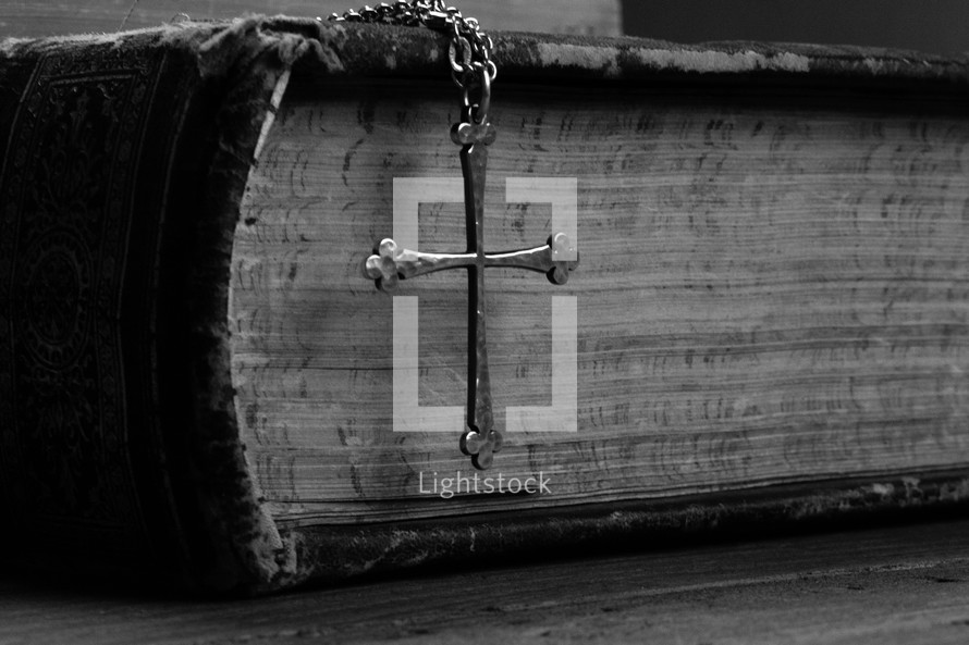 cross necklace draped over the side of a Bible 