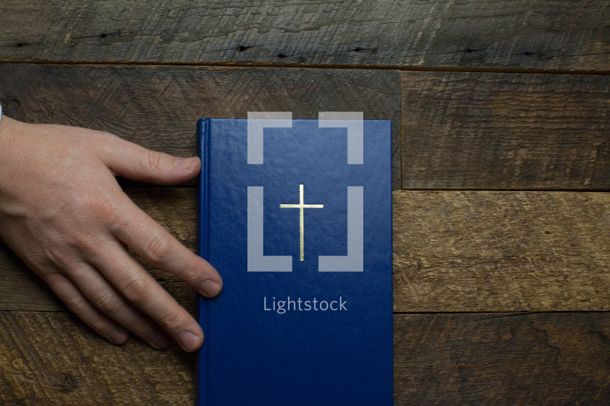 hand on the cover of a blue Bible 