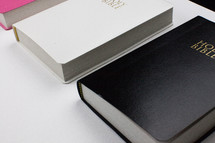 Three different colored Bibles on a white table.