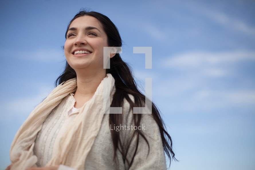 A smiling young woman in Biblical times under a blue sky.