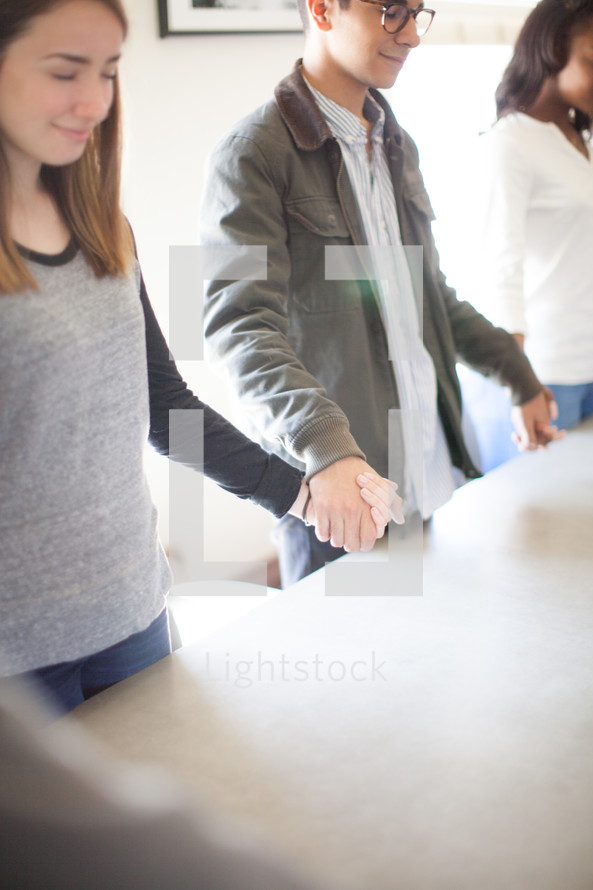 holding hands praying around a table 