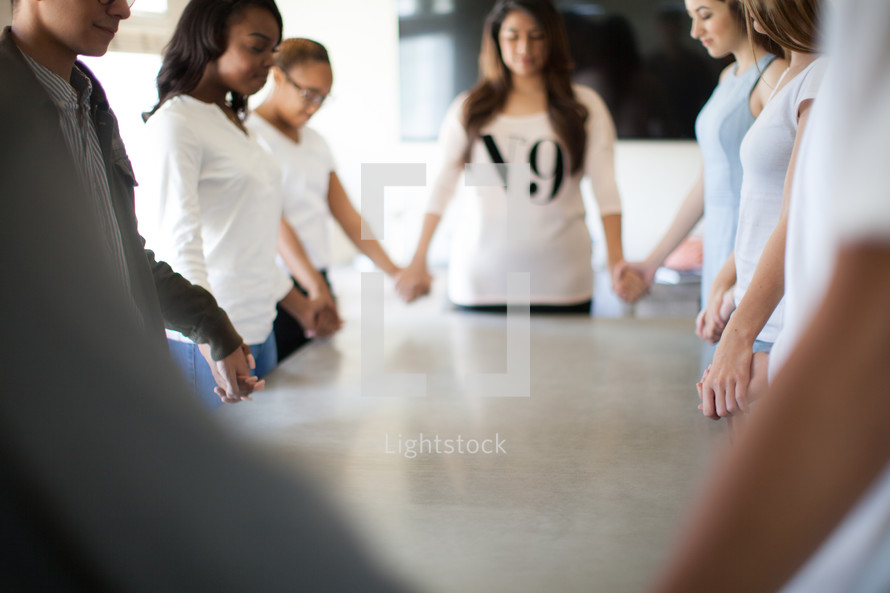 holding hands praying around a table 