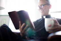 A minister sitting and reading a Bible with a cup of coffee.
