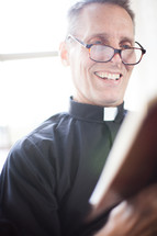A smiling minister reading the Bible.