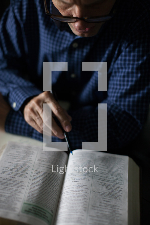 A man in a blue shirt reading the Bible.