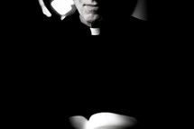 A minister wearing a clerical collar and black clothes.
