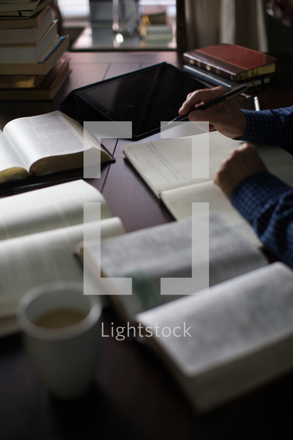 A man taking notes and studying the Bible at a desk with a cup of coffee.