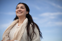 A smiling young woman in Biblical times under a blue sky.