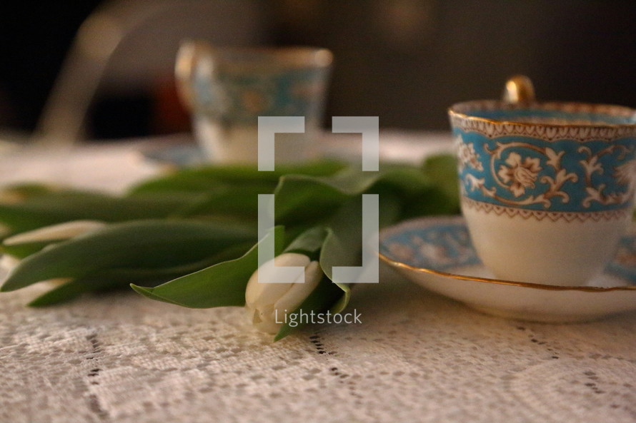 tulips and tea cups and saucers on a lace table cloth