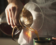 a man pouring coffee from a pour over dripper 