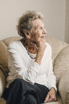 An elderly woman sitting and smiling.
