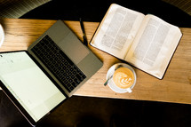a laptop computer, open Bible, and latte on a coffee table 