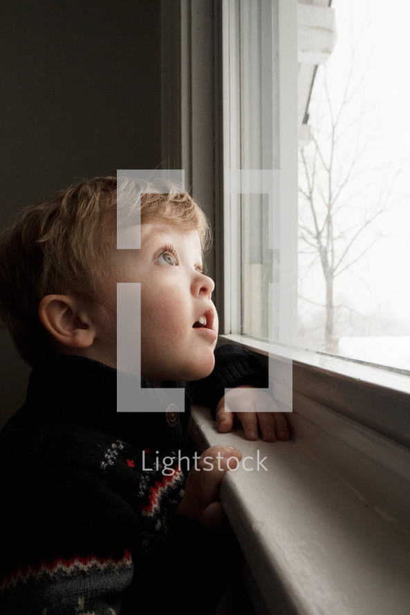 toddler boy looking out a window 