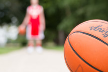 Basketball player in a red uniform with a basketball in the foreground.